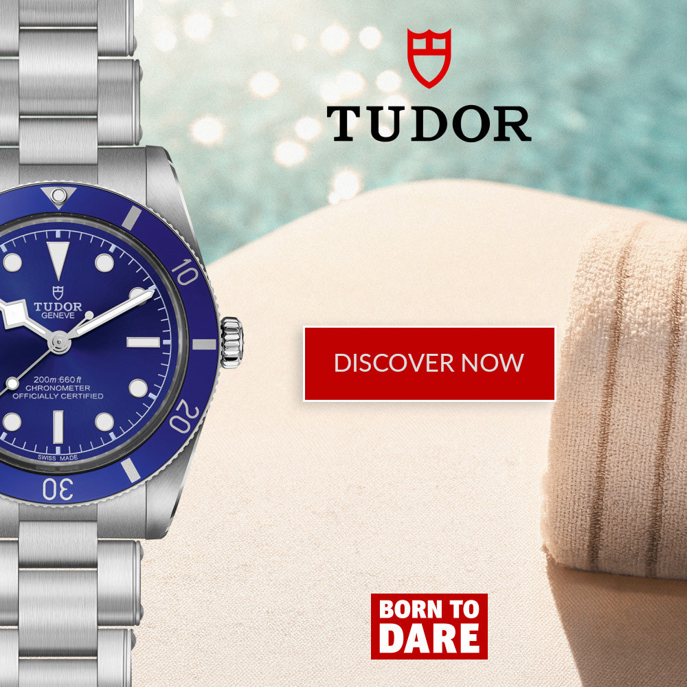 A Tudor watch with a blue dial and blue bezel, paired with a silver metal bracelet, shown on a beach-themed background with the Tudor logo and 'DISCOVER NOW' and 'BORN TO DARE' text overlays.